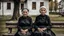 Placeholder: gloomy-looking old women sitting in black villager dress and wearing east european black head scharf on wooden bench in front of white old house outside in an authentic east european village, high detalied, professional photo, high qualit, high textures. The high-resolution image captures the essence of authenticity and realism, transporting the viewer to another time and place.