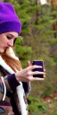 Placeholder: Brunette taking selfie.thick thighs,thick calves,flat belly,curvy fell. big head. Mantle is sewed of upcycled Denim and sewed together of camouflage pieces. Pieces' color are orange, cream and purple. It is with big bright purple felt tippet and birght-colored-hood is merged with colorful beanie. Big colored headphones (gold rings!) is merged with small felt cap with small visor. Style: Haute Couture in 1950's Africa, N.Y.C fashion in 2023