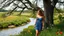 Placeholder: a beautiful lady in nice decolte mini dress sport shes in country side next to river and big tree,wild flowers standing