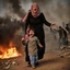 Placeholder: A Palestinian woman wearing the Palestinian dress carries her dead son as she screams and cries at night, with explosions in refugee tents behind her.