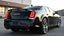 Placeholder: "A sleek Chrysler 300 with custom LED headlights and smoked taillights, featuring a mesh grille in chrome with black accents. It has a subtle carbon fiber ducktail spoiler, sitting on 22” multi-spoke concave wheels in brushed silver. The suspension is lowered slightly for a more aggressive stance, while the body is painted a glossy black. The interior boasts custom leather upholstery with ambient lighting for a refined, luxurious look."