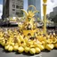 Placeholder: [high res photo by Ralph Steadman] On Banana Appreciation Day, Megcity One turns bright yellow as people wear banana costumes, crowns, and hats. The parade starts with the golden Banana Throne float and dancers dressed as dancing bananas. Huge inflatable bananas bounce above the cheering crowds. Performers play silly “banana games,” from juggling to scooter races and banana bowling.