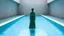 Placeholder: a woman standing in the middle of a rectangular swimming pool. The pool is made of concrete and has a blue-green color. The water is crystal clear and appears to be reflecting the light from the ceiling. The woman is wearing a long, flowing green dress with a high neckline and long sleeves. She is standing with her back to the camera, facing away from the camera. The walls is peaceful and serene.