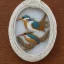 Placeholder: ivory brooch of a kingfisher, decorative design, classical ornament, highly ornate, highly intricate, highly detailed etching, marble carving, warm lighting, linen and wood backdrop