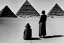 Placeholder: A 1922 woman looking at a black five-sided pyramid in the desert