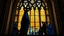 Placeholder: a majestic stained glass window inside a Gothic cathedral, featuring six stylized angular cats in geometric modern style. One large black cat, one blue-tinted cat, smaller cats in indigo and charcoal, one with a white face. Glowing yellow/amber eyes, dark silhouettes, simplified shapes. Intricate mosaic background in gold and bronze. Byzantine-inspired patterns. The stained glass window has lancet shapes, floral Gothic tracery, ornate lead frames. Light filters through, casting colorful glows in