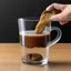 Placeholder: Pour milk into a clear glass cup. Inside the cup is a whole cookie.