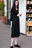 Placeholder: tall girl in black clothes, long dark wavy hair, outside an apothecary shop