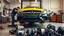 Placeholder: A car repair shop where two people in work clothes are repairing a black and yellow Benz CLS 550 with an eye-catching theme in a sophisticated and special repair shop where at the bottom of the image a collection of car engine parts are arranged on the floor with lighting and a classic atmosphere.