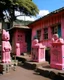 Placeholder: A rosy pink crumbling village designed in Hawaiian tiki statues painted by Stuart Davis