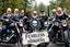 Placeholder: a very hard and tuff motorcycle bald gang, not old, posing with their Harley Davidsson bikes, some of them holding guns and shotguns, a logo sign with Falköpings HD Club, "Fearless sinners" Skulls and bones, skeletons