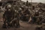Placeholder: movie scene: in a post apocalyptic future: people search the remains of civilization for remnants of civilization, their clothes are made of garbage and are improvised. they wear improvised ((very detailed)) masks for protection. The costumes are very detailed and made of garbage, metal parts, scrap metal, belts, bags, car parts, spikes, They are armed and look very dangerous. all is broken, extremely used, burnt, dangerous and rusty. The mood is very gloomy, dystopian and depressive.