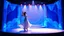 Placeholder: modern stage with blue theme artistic decoration , color full dynamic lighting, a beautiful lady in modern maxy dress with shining jwells dancing, 3D recursive fractal structure animating background