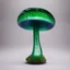 Placeholder: handmade glass art, a forest mushroom, the stem is made of clear transparent glass, small air bubbles and green glass stripes in the core of the stem, the shape is thick at the bottom and narrows at the top. The hat itself is made of purple clear glass where green fused glass is laid as a spiral from the middle outwards on top of the hat and is melted into the hat. The stem is set on a fused purple glass base with yellow glass stripes radiating from the center outwards. Placed in a window