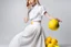 Placeholder: Sobre un fondo blanco de fotografía de estudio, un mujer rubia, vestida con camisa blanca sin abotonar y una amplia falda de color amarillo, juega con unos limones, fotografía de estudio, fotografía de moda. Disparo con cámara Leica