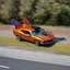 Placeholder: award winning car and driver photograph of a horsefly fighter-jet genetic-splice designed by only one vehicle per image painted metallic orange traveling at a high rate of speed, jet intake off of front center of vehicle and jet exhaust out the rear with bright blue flames painted on the hood and front quarter panels, bilaterally symetrical, more a high speed road vehicle