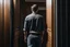 Placeholder: man in jeans and a shirt, back to the camera, standing in a row of doors, looking out through a doorway