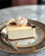 Placeholder: elegant cheesecake for a high-end cafe menu. Cheesecake should be presented on a stylish Turkish plate with a smooth creamy texture and graham cracker crust. Slice with cream rose topping or chocolate leaves for a touch of sophistication.", unreal engine, greg rutkowskу. Digital art, perfect composition, beautiful, thoughtful, insanely detailed octane render, popular on artstation, fine art photography 8k, photorealistic