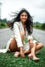 Placeholder: A stunningly ethereal Indian woman with cascading, tousled hair, captivating eyes, and a lovely smile sits gracefully on a grassy pavement. She is dressed in exquisite designer attire and shoes that perfectly complement her glowing skin. The windy weather adds a dynamic element to the scene, enhancing the fashion photograph's sense of movement and glamour. Each detail in the image exudes sophistication and elegance, creating a visual masterpiece that is both captivating and alluring.