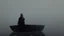 Placeholder: black robed monk in a small boat on quiet water in the mist