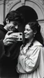 Placeholder: An old picture style of black and white mono very bad quality looks very old camera picture of Romeo and Juliet looking at iPhone of Juliet and both are laughing year 1140