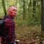 Placeholder: georges st pierre with a red plaid shirt, a backpack and a rifle in a creepy forrest with zombies