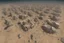 Placeholder: could you please create a visual image for an design project of different areas in a Holistic and Sustainable R comunal Spaces, Education and Job Training Centers, Integration of Mental Health Support' by the Rafah boarder in the dessert with buildings around it