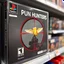 Placeholder: close up on a Playstation video game case on display on a store shelf for game titled "PUN HUNTERS", game case image is a pixelated video game image of a red sniper crosshair zeroing in on an anthropomorphic butter stick with wings, rated M for mature, original playstation game box satire,