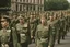 Placeholder: caucasian soldiers; marching in formation; away from camera; military parade; tight formation; shoulder to shoulder; marching along a street; green uniforms; medals and insignia; weapons in hands;