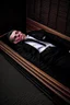 Placeholder: a man in black suit, red neck tie, white shirt, black pants, black shoe sleeping in a coffin