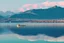 Placeholder: Sunny day, distant modern city, lake, lake reflections, people, mountains