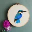 Placeholder: exquisite kingfisher in embroidery hoop, intricate, highly detailed, linen and wood backdrop