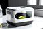 Placeholder: product design render on the table in the kitchen, A white color product that is rectangular parallelepiped with rounded corners, some mackerels visible through the product's open lid, with a black touch display on the front side of procuct whit a radioactive icon on it, minimal disign of white color, with a lid that opens upward with a hinge, a fine uv light inside the product, photorealistic