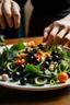 Placeholder: A plate of salad and pasta, with hands placing black olives on top of them