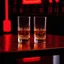 Placeholder: a table showing two whisky glasses in a dark bar room, red neon hues, van gogh style