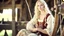 Placeholder: Photo is in sharp focus with high resolution and is a closeup of a beautiful and slender caucasian 17 year old teen girl with long wavy platinum blonde hair. She is wearing a medieval peasant dress with a coset. She is seated at a spinning wheel gazing at the viewer.