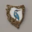 Placeholder: ivory brooch of a kingfisher, decorative design, classical ornament, highly ornate, highly intricate, highly detailed etching, marble carving, warm lighting, linen backdrop