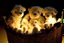 Placeholder: Cute but quirky stuffed animals lie in a carved basket on a soft sling, by candlelight