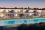 Placeholder: Sunset algarve in quinta do lago, a modern luxury villa apartments with 250 meters long and a pool on rooftop, overhang straight line terraces with black metallic beams and wood pergolas, with a separate clubhouse building facility with green roofs, overlooking the campus sport facility and inserted in the Ria Formosa Natural park, on a slope with pinus pinea, a wrap around low speed veicular road