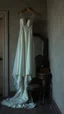 Placeholder: An old dusty wedding dress hanging on the wall , a cracked big mirror in front of makeup table by the wall of an abandoned room , Bosch painting style, sad and tragic and dark scenes