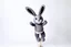 Placeholder: Scruffy fluffy grey puppet plush dust Bunny, holding with both hands onto a post while being blown vertically by the wind storm, extending vertically, comedic trope, on white background