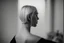 Placeholder: Mujer rubia de espaldas, retrato primer plano., iluminada desde desde el rostro hacia la cámara, Imagen en blanco y negro vaporoso, al estilo de la foto del fotógrafo Hugo Alonso.