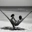 Placeholder: mujer sentada en una hamaca de madera en la playa, fotografía real, fotografía realizada con un cámara Fuji y objetivo de 35mm, fotografía en blanco y negro, tono años 60