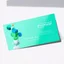 Placeholder: Professional business card mockup for a modern physiotherapist. The design features colorful geometric blocks and circles arranged to subtly resemble a spine or joint articulation, but in an abstract artistic way. Colors: Vibrant mint green, electric blue, and warm terracotta. Layout: Asymmetric and dynamic but organized. Texture: Premium matte paper finish. Lighting: Soft studio lighting with natural shadows. Design aesthetic: Bauhaus inspired, clean lines, approachable, distinct and memorable.