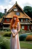 Placeholder: full body and headshot of a skinny Cleopatra, with long wavy ginger hair, in a floaty dress, standing on a village green, with thatched roof cottages behind