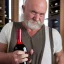 Placeholder: burly ugly 58 year old man bald with short beard and tank top manly chest chooses a bottle of wine in a cellar full of wine bottles dramatic light angry eyes highly detailed