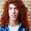 Placeholder: teen, male, with long red curly hair, real photo, soft lighting