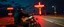 Placeholder: The kebab man driving fast on his motorcycle, fire from the exhaust, widescreen picture, empty road on the country at night, comic style, no helmet and he have a long black beard, neon kebab signs along the road, jesus at his cross