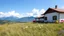 Placeholder: pretty moder villa wide grass yard in country side nice flowers in sides,nice blue mountains at distant,white cloudes in blue sky