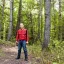 Placeholder: Georges st pierre with a red plaid shirt a jean, a military backpack and a shotgun in the forest